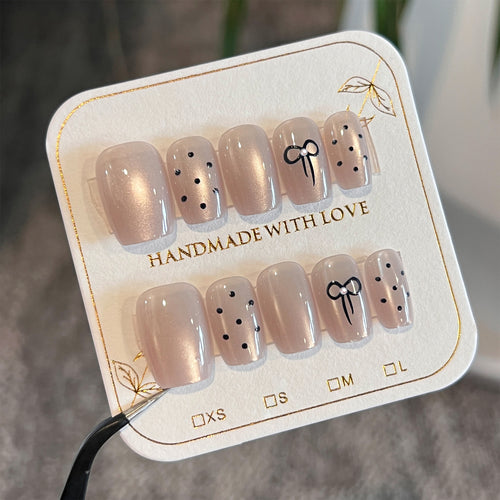 Artificial nail extensions with decorative bows and dots Bowlift