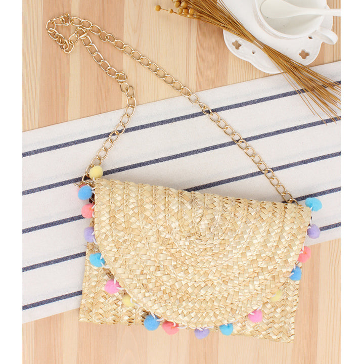 Clutch made of handwoven natural material with decorative pompons Bowlift