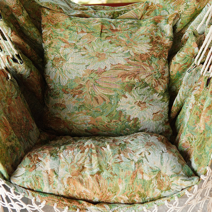 Woven hammock chair with padded floral cushions and macramé fringe Bowlift