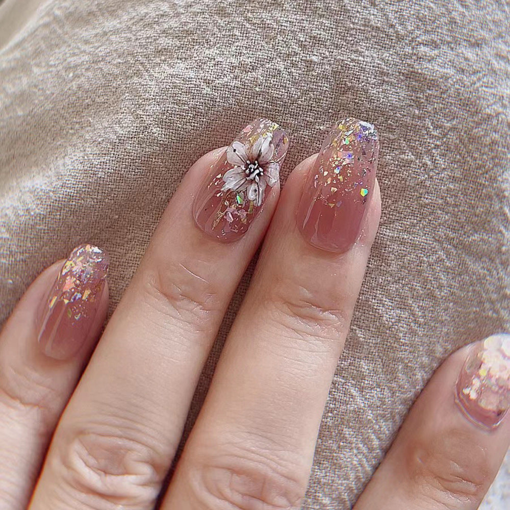 Artificial nail extensions with floral design and glitter accents Bowlift