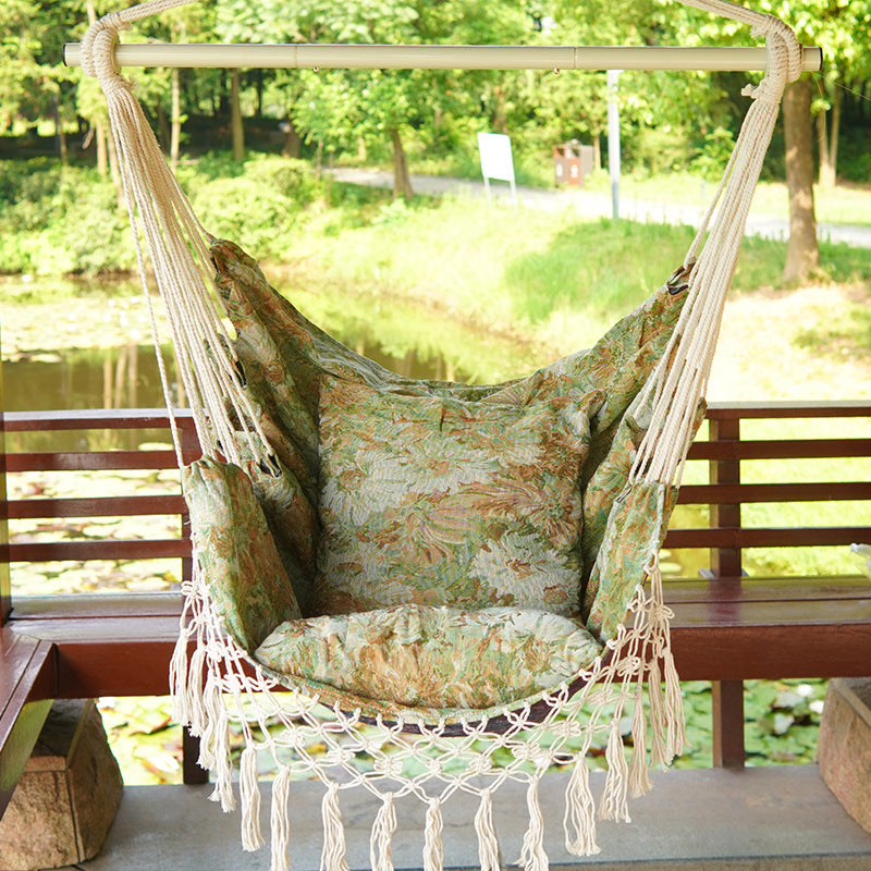 Woven hammock chair with padded floral cushions and macramé fringe Bowlift