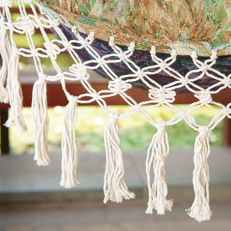 Woven hammock chair with padded floral cushions and macramé fringe Bowlift