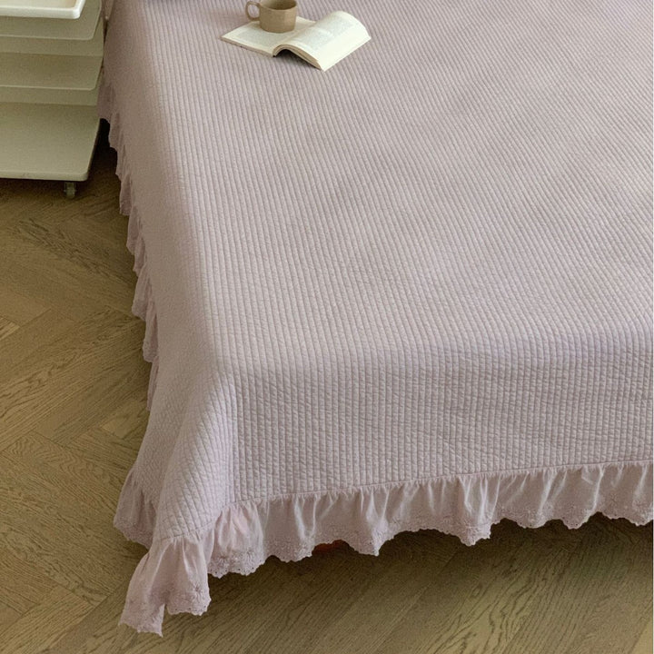 Quilted bedspread with ruffled trim and fine quilted texture