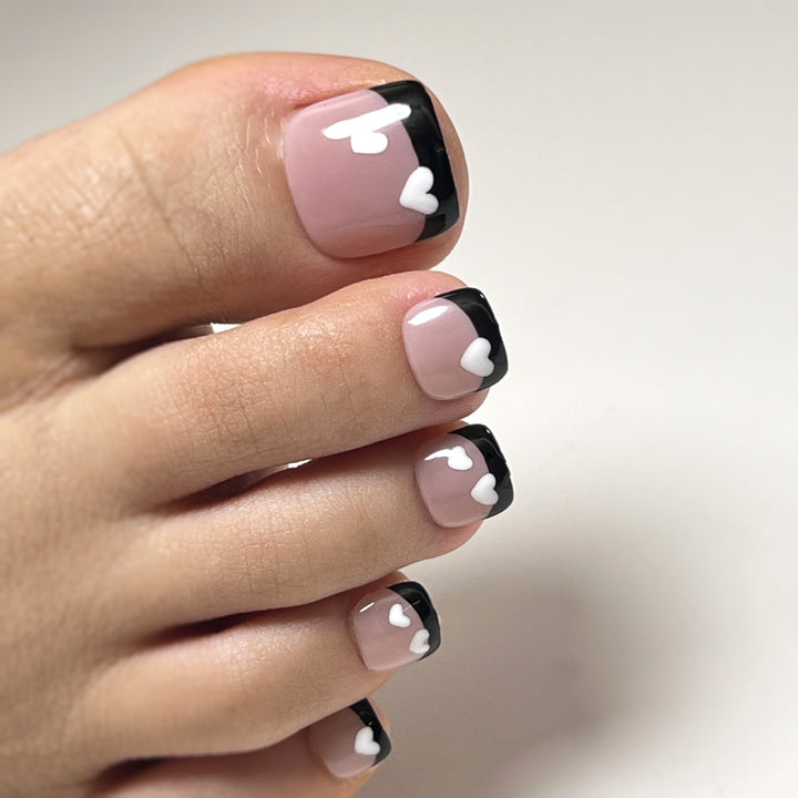Artistic toenail design with heart motifs and modern black-and-white design Bowlift
