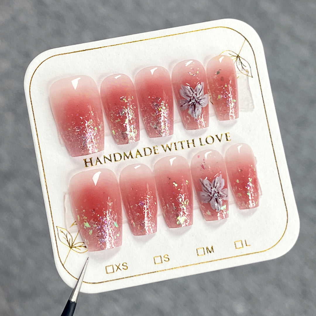 Artificial nail extensions with floral design and glitter accents Bowlift