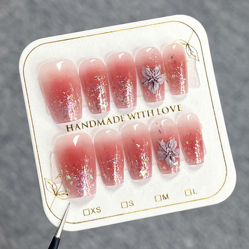 Artificial nail extensions with floral design and glitter accents Bowlift