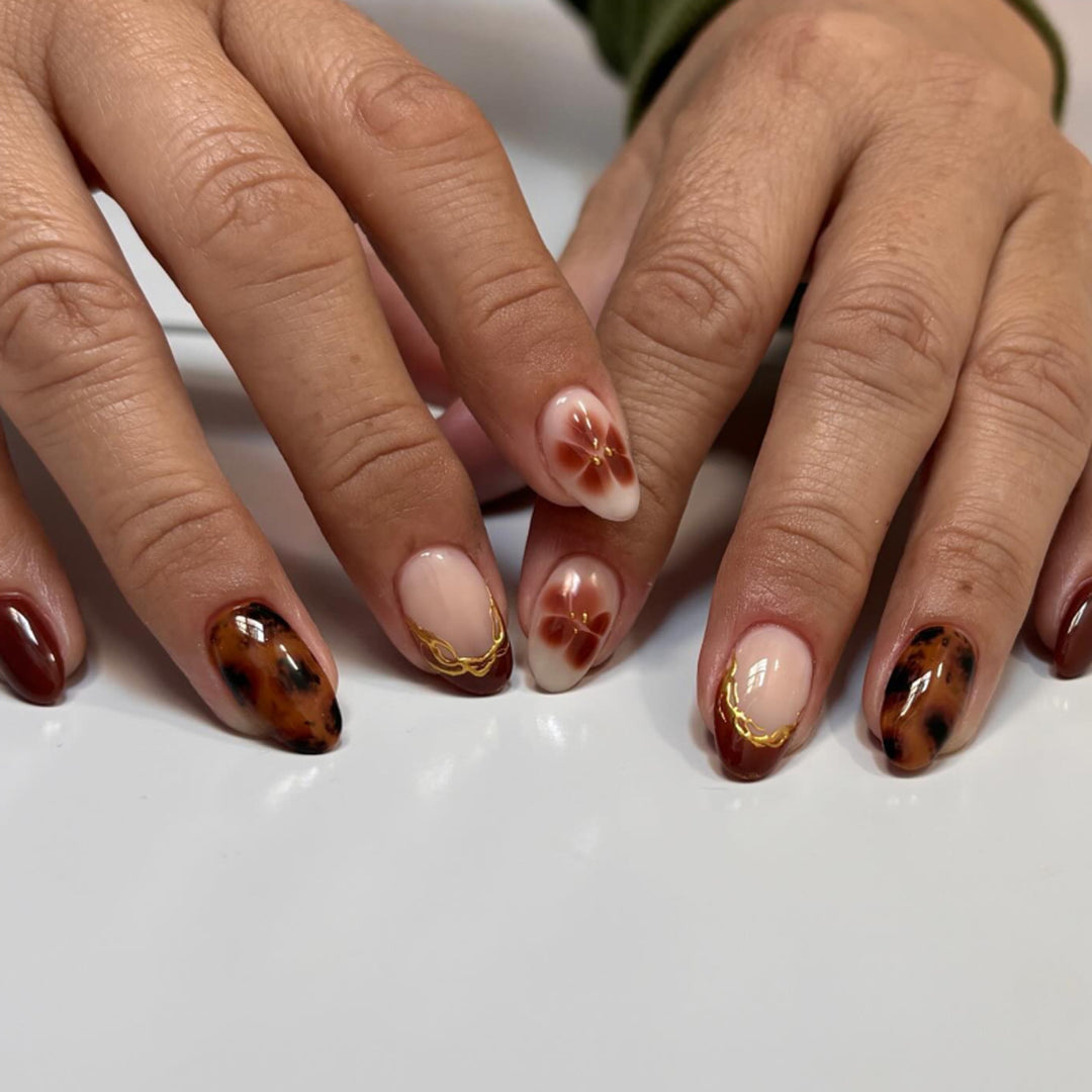 Artful acrylic nails with floral embellishments and glitter accents Bowlift